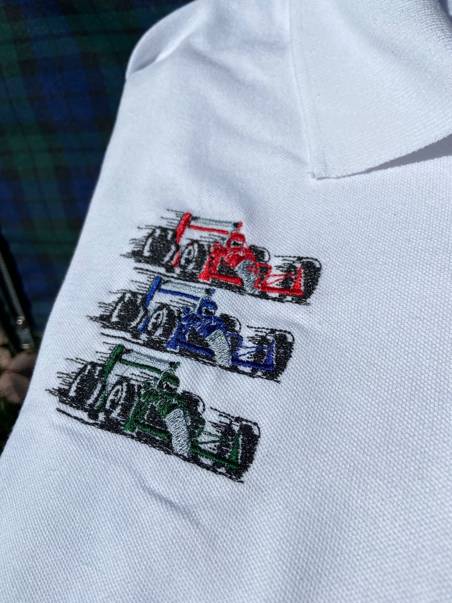 Casual classy vintage style white polo with Athletic and Affluent Race Team embroidery. Red blue and green racecars are displayed on the crisp white polo.
