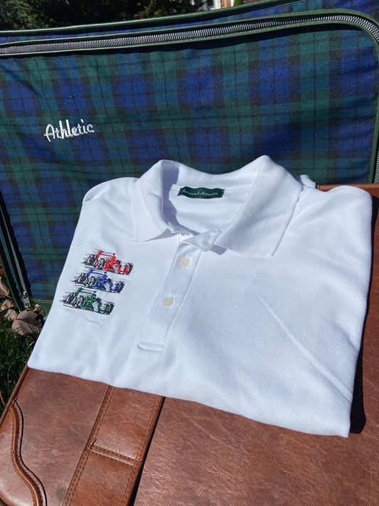 Casual classy vintage style white polo with Athletic and Affluent Race Team embroidery. Red blue and green racecars are displayed on the crisp white polo in front of an old-school plaid and vintage leather luggage set.